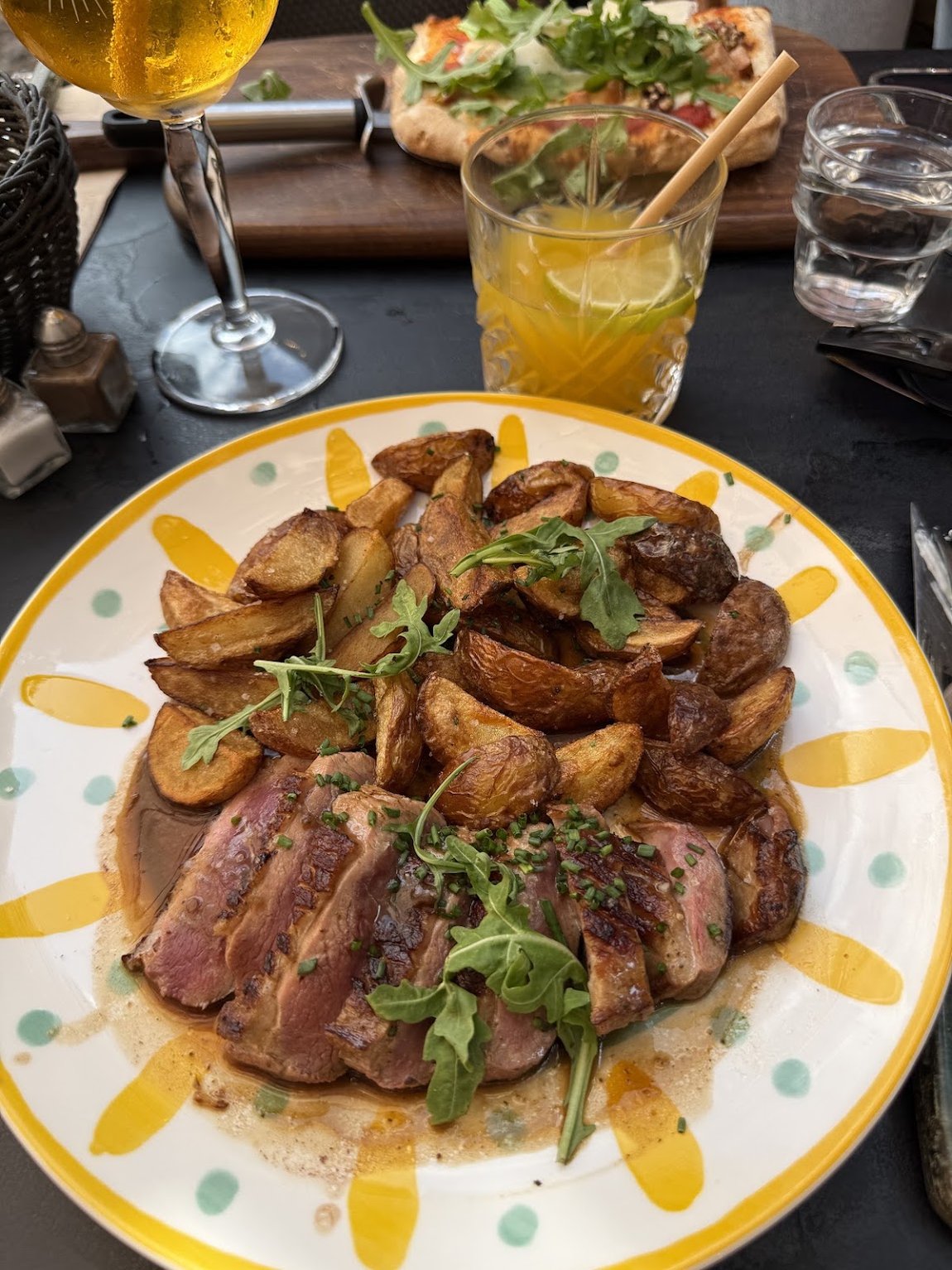 Magret de canard tranché et pommes de terre grenaille frites, dans une assiette blanche à motifs jaunes.